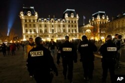 在敬拜者抵达巴黎圣母院大教堂参加圣诞夜弥撒时，法国警察在教堂附近巡逻（2016年12月24日）