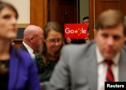 A demonstrator holds up a sign in the doorway as Google CEO Sundar Pichai testifies at a House Judiciary Committee on greater transparency in Washington, Dec. 11, 2018.