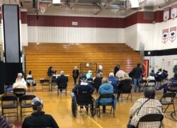 资料照片：以老人为主的民众在马里兰州蒙哥马利郡由某高中体育馆临时改建的新冠疫苗接种中心接种疫苗后坐在观察区内。(2021年3月22日)