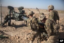 FILE - photo provided by Operation Resolute Support, U.S. Soldiers with Task Force Iron maneuver an M-777 howitzer, so it can be towed into position at Bost Airfield, Afghanistan.