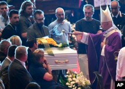 Cardinal Angelo Bagnasco blesses the coffin of nine-year-old Samuel Robbiano during a funeral service for some of the victims of a collapsed highway bridge, in Genoa's exhibition center Fiera di Genova, Italy, Aug. 18, 2018.