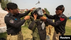 A technician from Pakistan's top bomb disposal unit is helped into his protective suit during a demonstration at the unit's headquarters in Peshawar, Sept. 12, 2013.