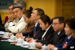 A delegate in traditional Uighur dress listens to a speaker during a group discussion meeting with delegates from China's Xinjiang Uighur Autonomous Region on the sidelines of China's National People's Congress (NPC) at the Great Hall of the People in Beijing, March 12, 2019.