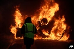 Un manifestante observa un carro incendiarse cerca de la avenida de los Campos Elíseos durante una manifestación el sábado 1 de diciembre de 2018, en París.