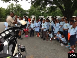 Corporal Randy Green talks with campers about being a motorcycle cop, July 2015. (J. Taboh/VOA)