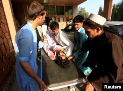 2018年6月16日在阿富汗贾拉拉巴德发生汽车炸弹事件后，一名受伤男子的亲属将他送入医院。