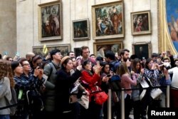 بازدیدکنندگان لوور در مقابل تابلوی موتا لیزا