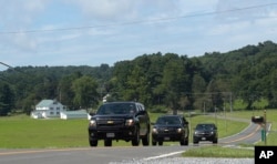 Official vehicles drive down a road near Camp David, Md., Aug. 18, 2017.