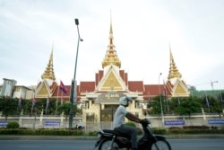 រូបឯកសារ៖ បុរស​ម្នាក់​បរ​ម៉ូតូ​កាត់​មុខ​រដ្ឋ​សភា​ក្នុង​ក្រុង​ភ្នំពេញ កាលពីល្ងាចថ្ងៃទី០២ ខែឧសភា ឆ្នាំ២០១៨។ (អូន ឆេងប៉រ/VOA)