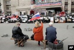 亲俄罗斯活动人士挥舞着俄罗斯旗帜，坐在被亲俄分子占领的顿涅茨克州政府大楼外的隔离物上。（2014年4月23日）