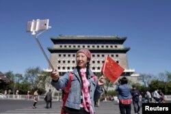 지난달 중국 베이징의 관광 명소인 정양문 앞에서 오성홍기를 든 여성이 사진을 찍고 있다.