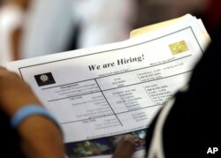 In this Thursday, June 21, 2018 photo, a job applicant looks at job listings for the Riverside Hotel at a job fair hosted by Job News South Florida, in Sunrise, Fla.