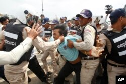 A Worker Union member, Suth Chet, 36, center, is beaten by district security personnel during a protest rally at a blocked street near National Assembly, in Phnom Penh, Cambodia, April 4, 2016.