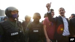 Venezuela's opposition leader and self proclaimed president Juan Guaido gestures next to soldiers outside La Carlota air base in Caracas, Venezuela, Tuesday, April 30, 2019.