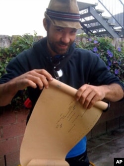 This fellow is winding (or unwinding) a piano roll. The punched holes engage sprockets in a player piano that, in turn, connect to the strings that play the corresponding note.