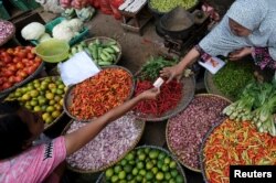 Seorang penjual sayuran mengambil uang dari pembelinya di sebuah pasar di Jakarta, 2 Juni 2017. Bank Indonesia memperkirakan inflasi 2019 akan berkisar 3,5 persen.