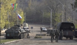 Pengambilan gambar dari video AFPTV ini menunjukkan bendera Rusia dan Azerbaijan berkibar di samping penjaga perdamaian Rusia di pos pemeriksaan dekat Shusha di sepanjang jalan Goris-Stepanakert, 17 November 2020.