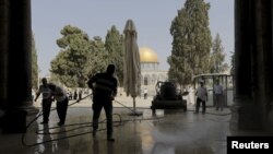 Warga Palestina membersihkan kompleks Al-Aqsa usai bentrokan dengan polisi Israel pertengahan bulan lalu.