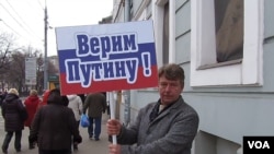 俄罗斯吞并克里米亚后，当局去年3月在莫斯科组织亲政府支持普京集会游行。普京的一名支持者手举标语：我们信任普京。（美国之音白桦拍摄）