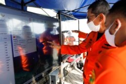 Para petugas tim SAR memperhatikan peta lokasi jatuhnya pesawat Sriwijaya Air SJ 182 di posko di Pelabuhan Tanjung Priok, di Jakarta, Senin, 11 Januari 2021. (Foto: Willy Kurniawan/Reuters)