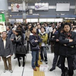 Train passengers wait at Tokyo's Shinagawa station after service was halted