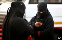 A burqa clad Indian woman checks her phone at a street in Hyderabad, India, March 24, 2015.