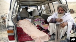 一位阿富汗老人3月11日坐在据称被一名美军士兵打死的村民尸体旁