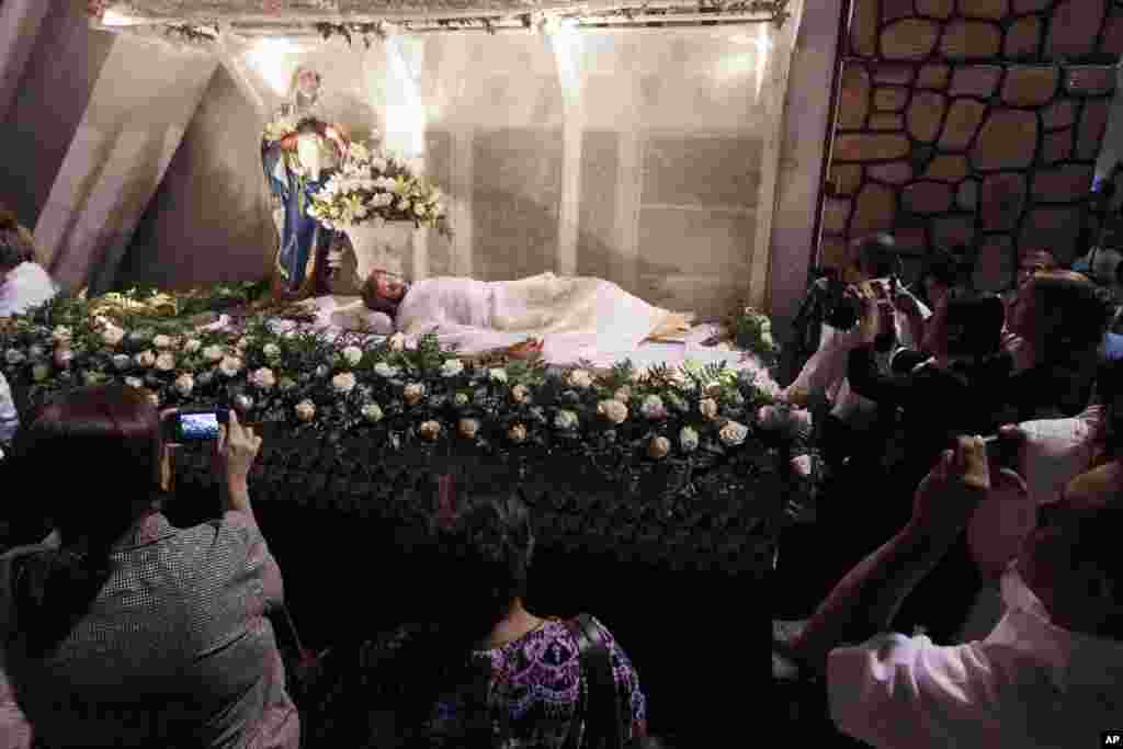 Jemaat mengambil foto patung Yesus Kristus pada misa Pekan Suci di Gereja Divine Mercy di Panama City, Panama (28/3). (AP/Arnulfo Franco)