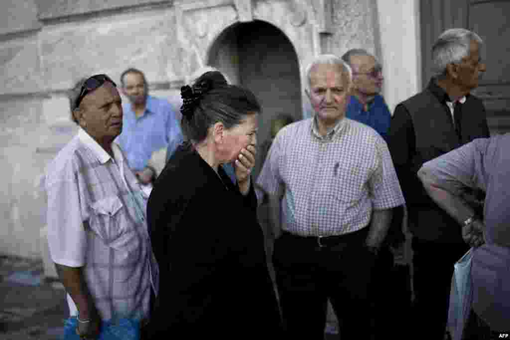 Para pensiunan menunggu di luar sebuah kantor cabang National Bank of Greece untuk mendapatkan pensiunnya (29/6) di Athena. (​AFP/Angelos Tzortzinis)