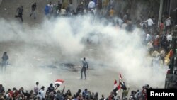 Para pengunjuk rasa berlarian menghindari semprotan gas air mata yang digunaoakn oleh polisi anti huru-hara di untuk membubarkan massa di lapangan Tahrir, Kairo (23/11)