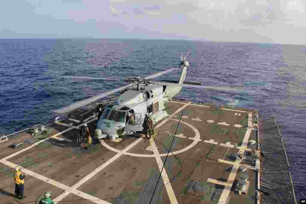 Sebuah helikopter AL AS mendarat di Destroyer USS Pinckney dalam pertukaran kru sebelum kembali melakukan misi pencarian dan penyelamatan untuk pesawat Malaysia yang hilang dengan nomor penerbangan MH370 di Teluk Thailand, 9 Maret 2014.&nbsp;