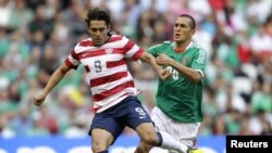 Hérculez Gómez (kiri) mempertahankan bola dari pemain Meksiko Jorge Torres Nilo dalam partai CONCACAF antar AS dan Meksiko (15/8).