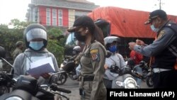 Para petugas Satpol PP memeriksa para pengendara motor di sebuah pos pemeriksaan di tehang penerapan PPKM darurat untuk meredam pandemi virus COVID-19 di Denpasar, Bali, 8 Juli 2021. (Foto: Firdia Lisnawati/AP)