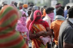 FILE - Migrant laborers from other states looking for work gather on a street on the outskirts of Jammu, India, Sept.27, 2020.