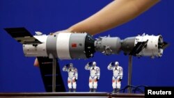 资料照： 在酒泉卫星发射中心展示的中国神舟9号飞船与三名中国宇航员的模型。（2012年6月15日）