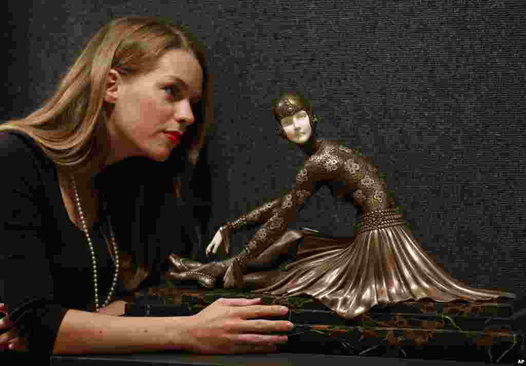 Seorang karyawan berpose dengan patung yang dibuat dari perunggu dan gading berjudul &#39;Tanara&#39; karya Chiparus Demetre yang dipajang di rumah lelang Bonhams di London. 