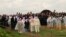Yazidi priests release doves into the air after blessing a mass grave while the exhumation team stands by to begin their work in Kocho, Iraq, March 15, 2019. 