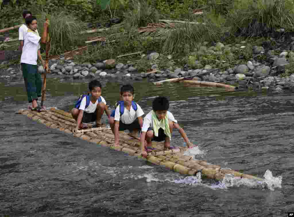 Tiga murid SD menyeberangi sungai dengan rakit untuk menghadiri pembukaan kelas tahun ajaran 2013-2014, di sebuah desa terpencil di kota Rodriguez, provinsi Rizal, sekitar 50 kilometer sebelah timur Manila, Filipina.