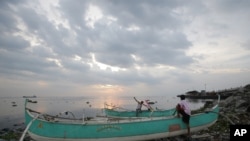 Nelayan Filipina tengah memeriksa perahu mereka yang mereka tambatkan di atas onggokan sampah di desa pantai Navotas, Manila Utara, Filipina (14/7). Warga Filipina tengah bersiap menghadapi badai tropis Rammasun, yang diperkirakan akan mencapai daratan di provinsi Catanduanes Selasa pagi (15/7).