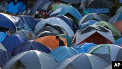 In this Nov. 5, 2019, photo, a migrant walks through a refugee camp in Matamoros, Mexico. The camp is an outgrowth of the Trump administration’s “Remain in Mexico” program.
