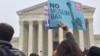 A protester waves a sign at a rally outside the U.S. Supreme Court in Washington, April 25, 2018 (V. Macchi/VOA). Opponents of the Trump administration’s travel ban say the policy discriminates against Muslims, 