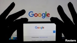 A smartphone and computer screen display the Google home page. U.S. presidential elections spur online searches for information about moving to Canada.