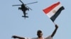 A military helicopter flies over an opponent if Egyptian Islamist President Mohammed Morsi as he waves a national flag, in Tahrir Square in Cairo, July 2, 2013.