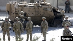 北约军事使命团的士兵站在阿富汗喀布尔发生的自杀式汽车炸弹爆炸现场旁(资料照片)