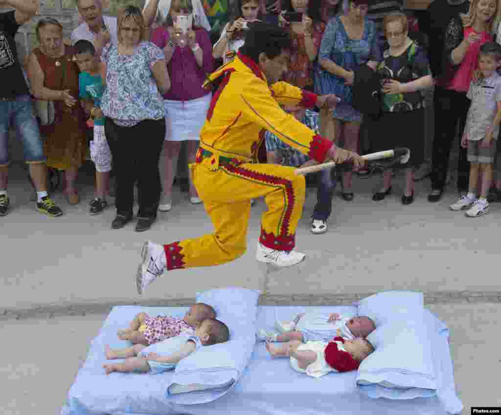 Seorang pria melompat di atas bayi-bayi di atas kasur, pada perayaan tradisional Corpus Christi di kota Castrillo de Murcia, Spanyol utara.