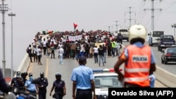 A polícia observa as pessoas a reunirem-se durante a manifestação para protestar contra o aumento do custo de vida, a corrupção em todo o país e para exigir a realização de eleições locais, em Luanda, a 20 de Março de 2021.