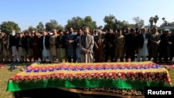 مردان افغان در برابر تابوت ملالی میوند روزنامه نگار در جلال آباد در افغانستان نماز می خوانند. ۱۰ دسامبر ۲۰۲۰