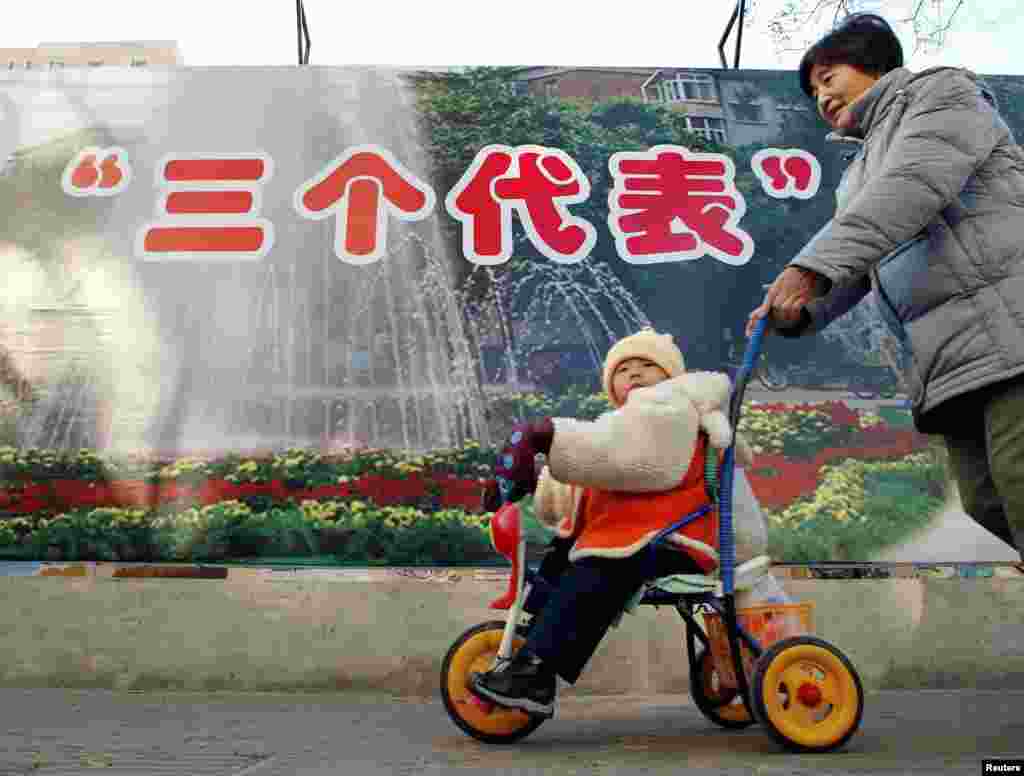 2002年11月28日，北京的一位母亲推着婴儿走过&ldquo;三个代表&rdquo;思想的宣传牌。&ldquo;三个代表&rdquo;思想被认为是江泽民的重要理论贡献。