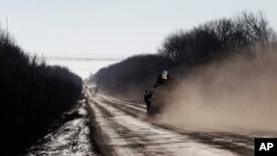 Sebuah kendaraan lapis baja Ukraina melintas di jalan yang memanjang dari kota Artemivsk sampai Debaltseve, Ukraina (17/2). (AP/Petr David Josek)
