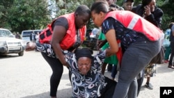 Wafanyakazi wa Red Cross wakimsaidia mwanamke ambaye alifikwa na majonzi baada ya kufahamu kuwa ndugu yake ameuwawa katika shambulizi la kigaidi, Jumatano, Jan. 16 2019, katika jengo la kuhifadhi maiti huko Chiromo Nairobi, Kenya. 